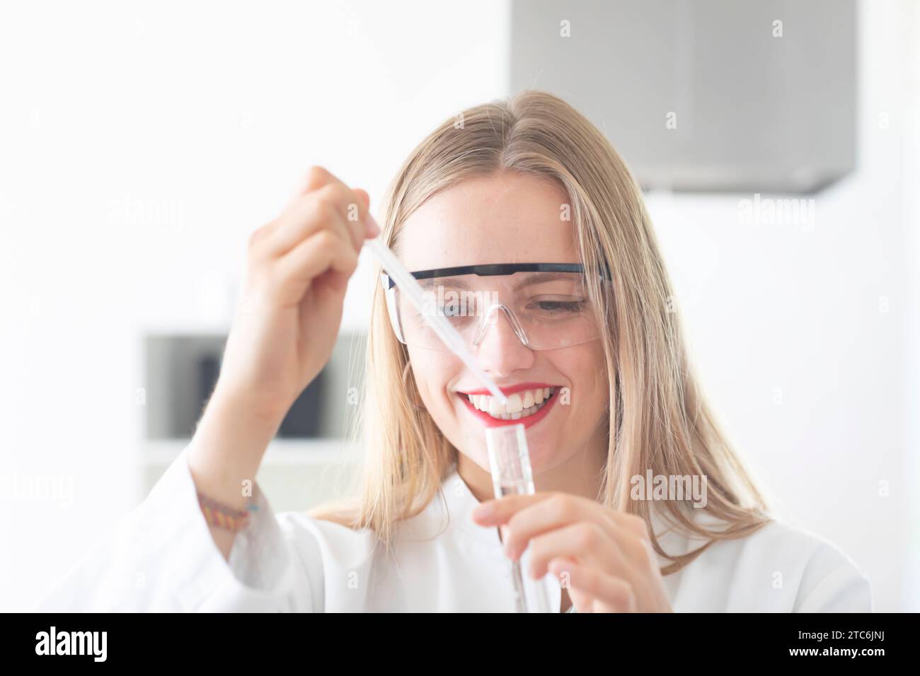 Junge Wissenschaftlerin mit Laborbrille Pipettieren Stockfoto