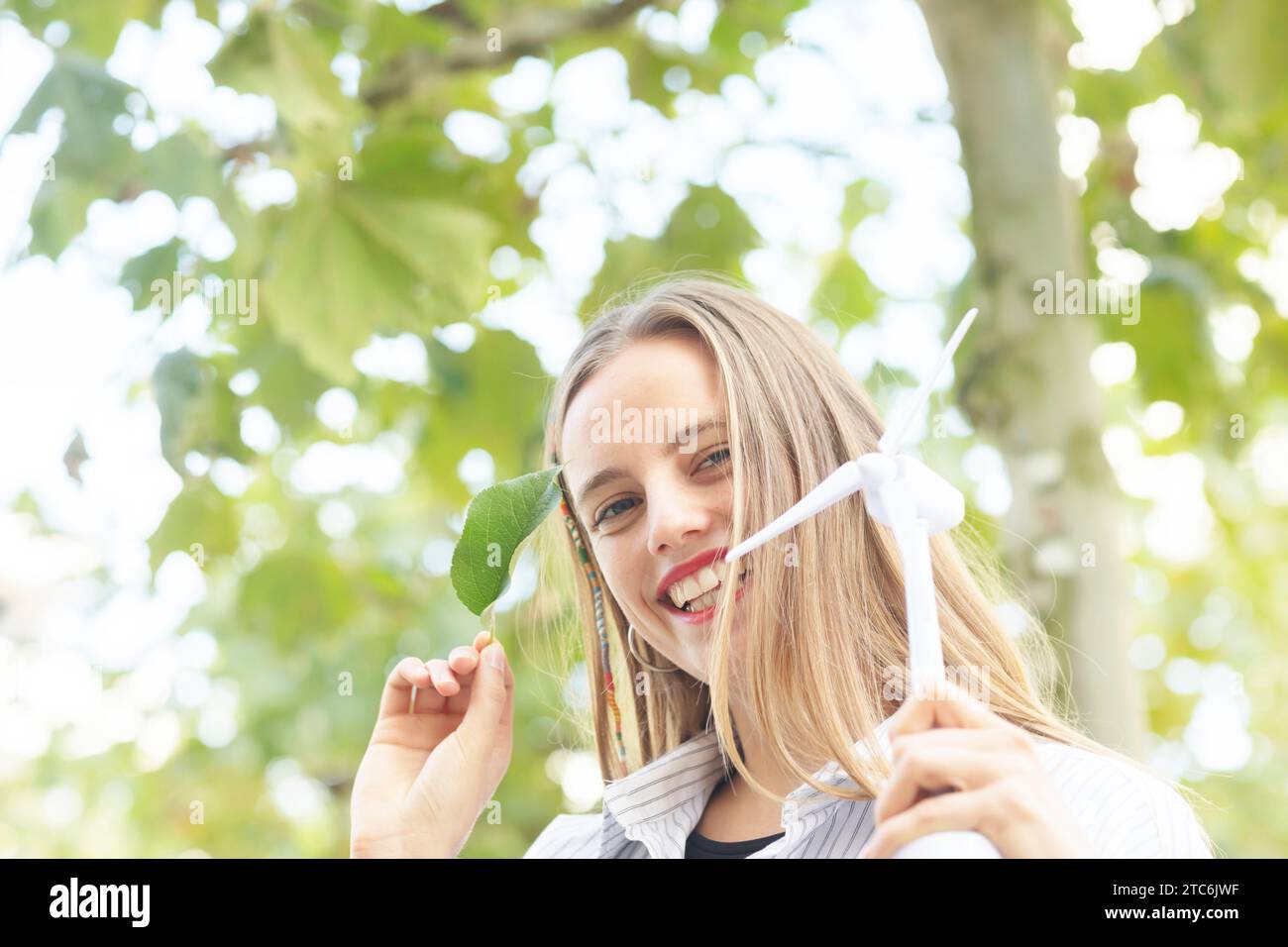 Junge Frau mit blonden langen Haaren, die grüne Klimazeichen hält Stockfoto