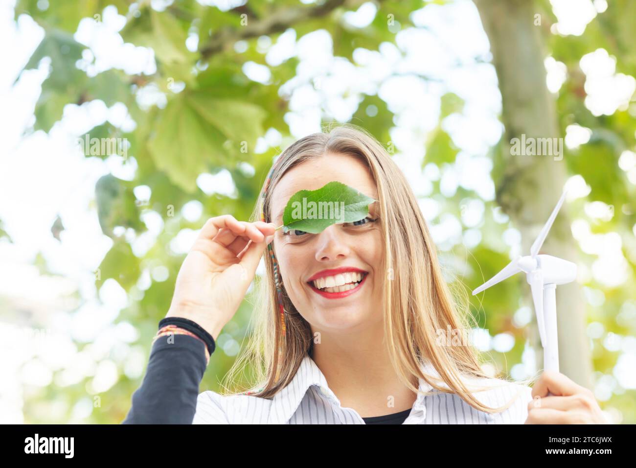 Junge Frau mit blonden langen Haaren, die grüne Klimazeichen hält Stockfoto