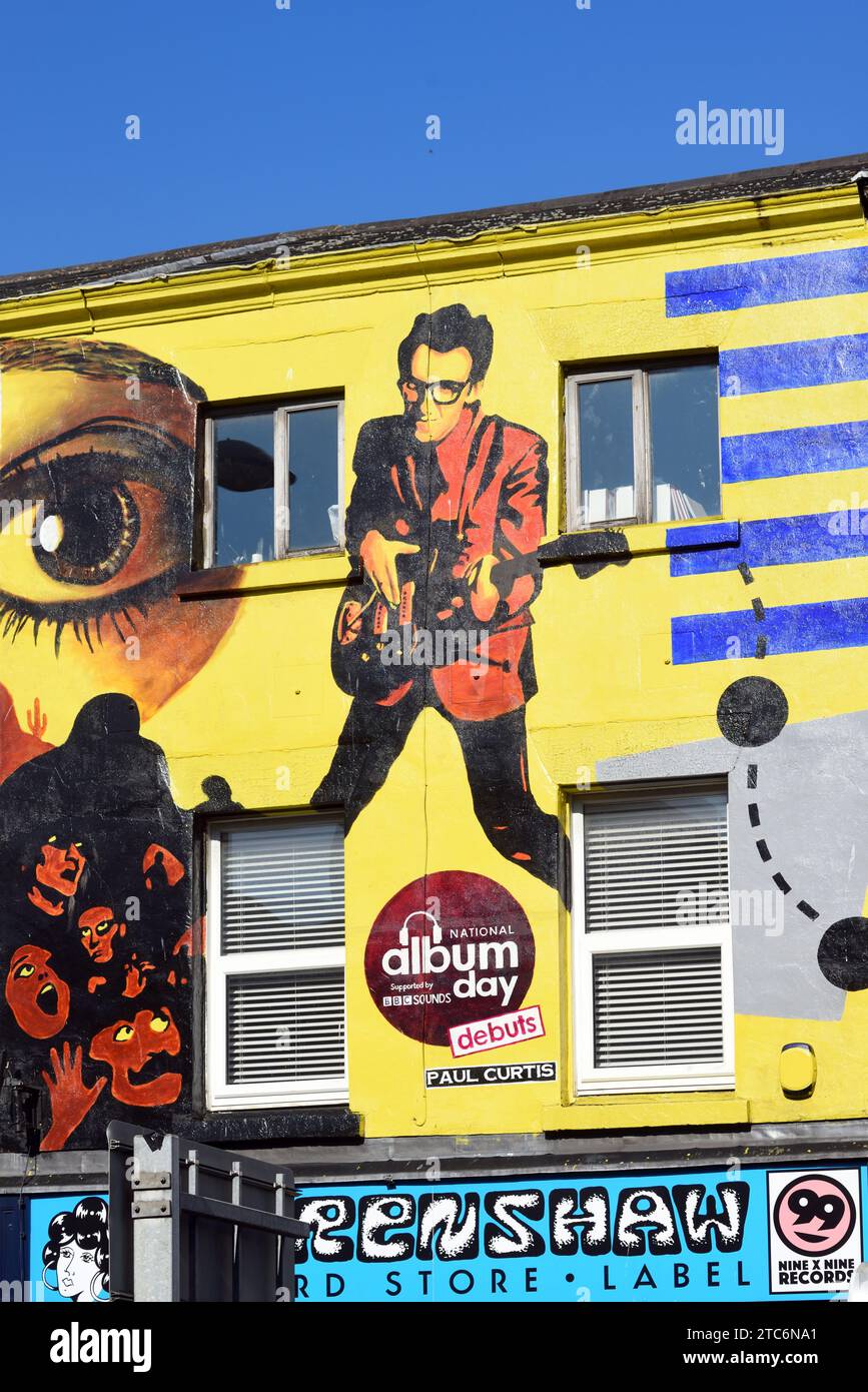 Record Store oder Music Shop mit Wandmalerei von Elvis Costello inspiriert von seinem Debütalbum My AIM Is True (1977), Liverpool England, Großbritannien Stockfoto