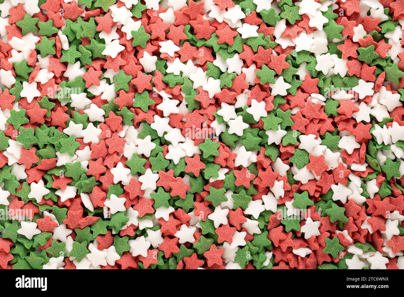 Sternförmige Zuckerstreuer. Hintergrund von grünen, roten und weißen Konfetti-Bonbons, Süßwaren aus Zucker und Reis. Stockfoto