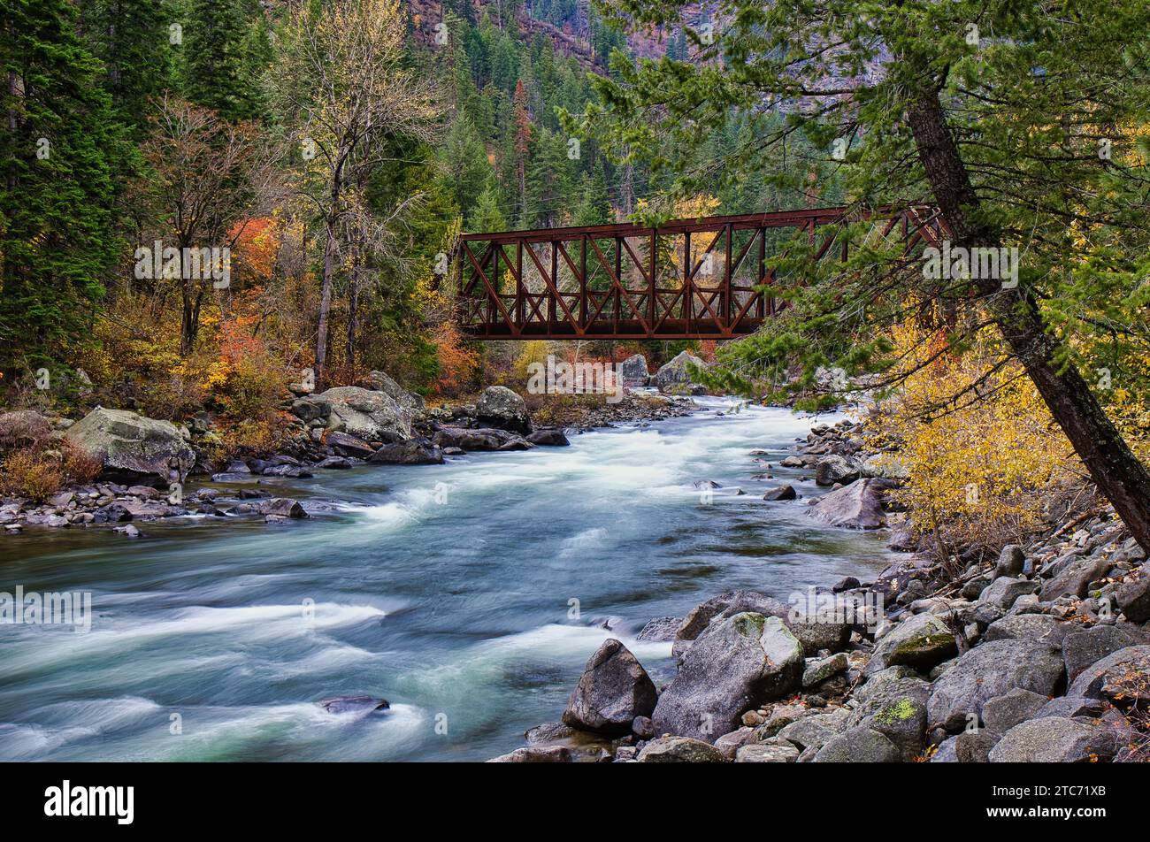 Ein Fluss, der sich durch einen Wald im US-Bundesstaat Washington schlängelt, mit Herbstlaub und felsigen Ufern Stockfoto