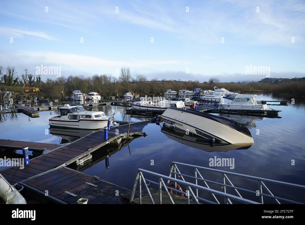 Ein kentertes Boot im Hafen von Leitrim Village in Co Leitrim, nach einem Tornado und starkem Wind am Sonntag, zerriss ein Dach von einem Gebäude und ließ Trümmer auf einer Straße verstreut zurück. Bilddatum: Montag, 11. Dezember 2023. Stockfoto