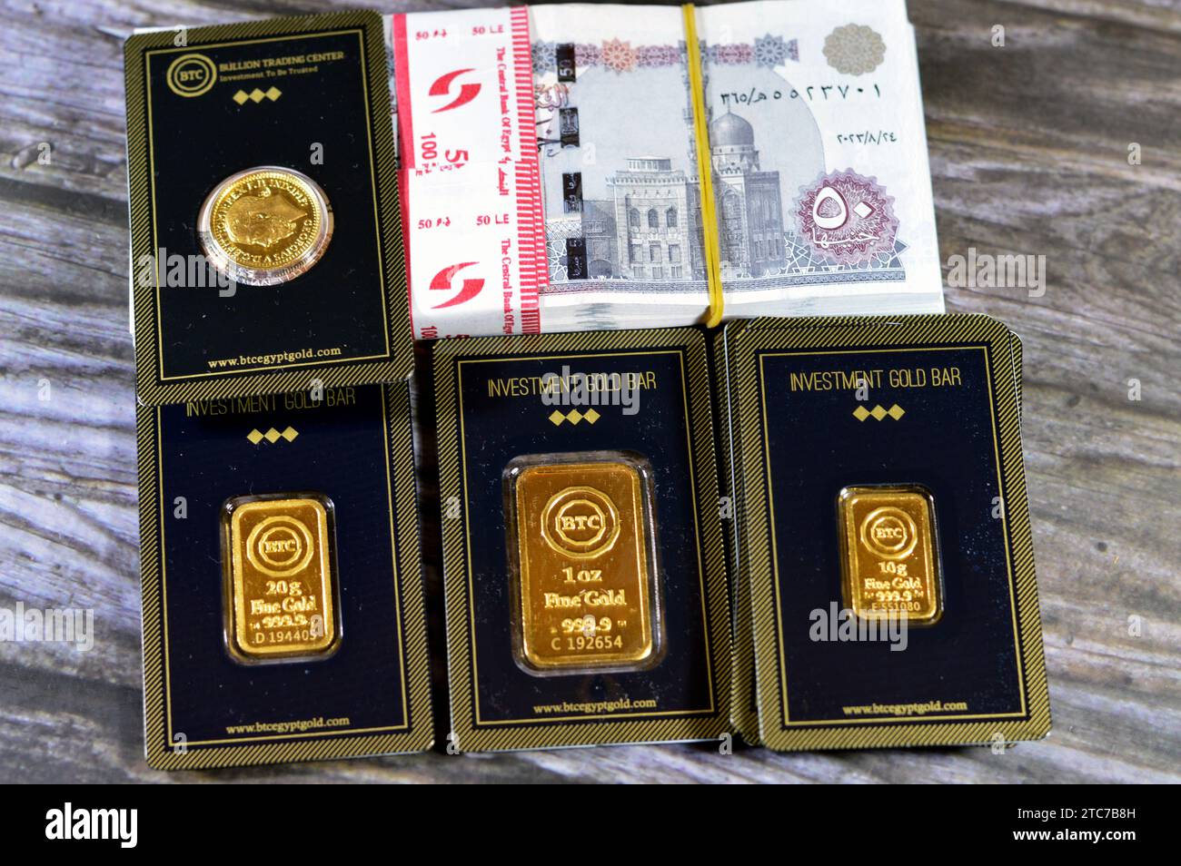 Kairo, Ägypten, 8. Dezember 2023: 24 Karat BTC Bullion Trading Center reines gelbes Gold aus Barren und souveränen Münzen und ein Stapel ägyptischer Geldbanknot Stockfoto