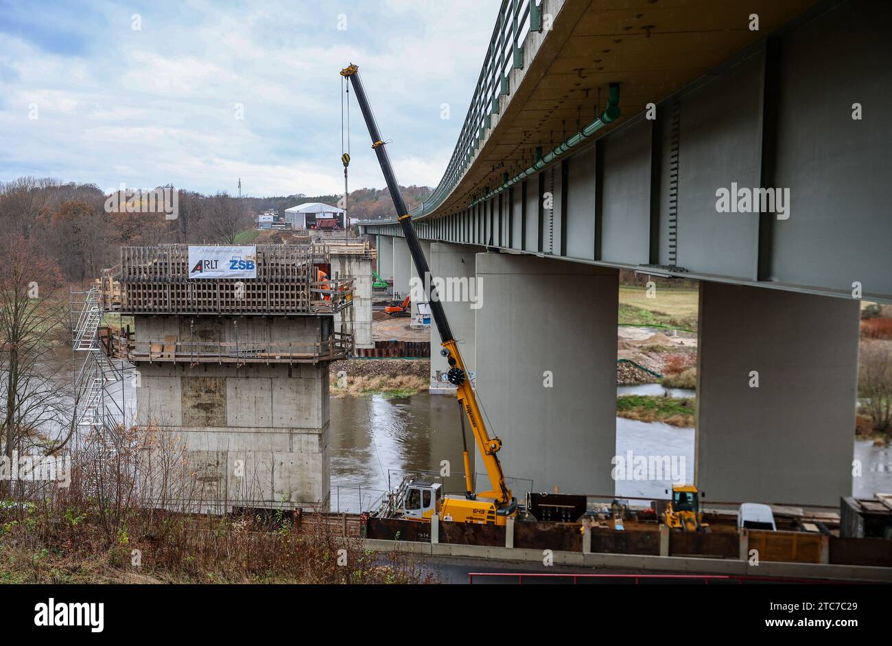 Grimma, Deutschland. Dezember 2023. Der vordere Abschnitt der neuen Mulde-Brücke wird in der schrittweisen Startmethode neben die A14 verschoben. Am selben Tag begann die erste Verschiebung des südlichen Stahlaufbaus. Das Bauwerk ersetzt die alte Brücke aus den 1970er Jahren Die neue Brücke wird 361 Meter lang sein. Die Projektkosten in Höhe von 81 Millionen Euro werden vom Bund getragen. Die Umsetzung ist für 2027 geplant. Kredit: Jan Woitas/dpa/ZB/dpa/Alamy Live News Stockfoto