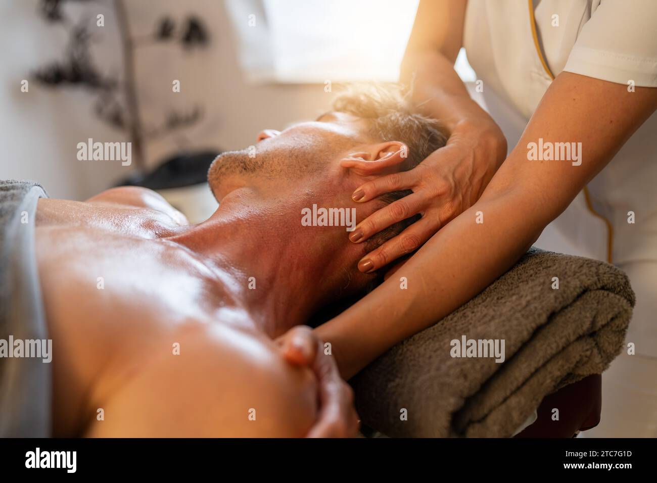 Therapeut, der eine Nackenmassage bei einem männlichen Kunden in einer Spa-Umgebung durchführt: Wellness Hotel Konzept Bild: Stockfoto