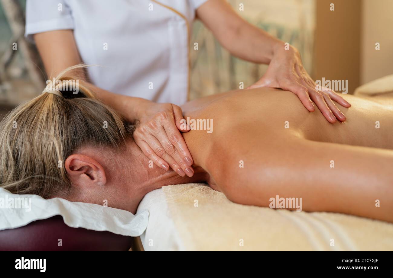 Die Hände einer Massage-Therapeutin als Arbeit auf dem Rücken einer Kundin im sap Hotel Stockfoto