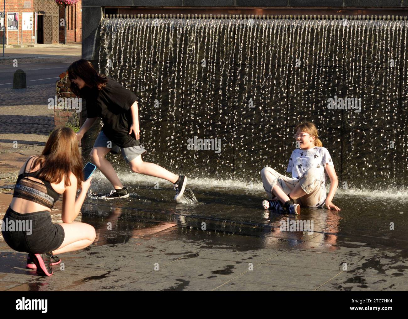 Mädchen im Teenageralter, die Spaß daran haben, Fotos zu machen und in einem Brunnen am Bernsteinmuseum in Danzig, Polen, Europa, EU nass zu werden Stockfoto