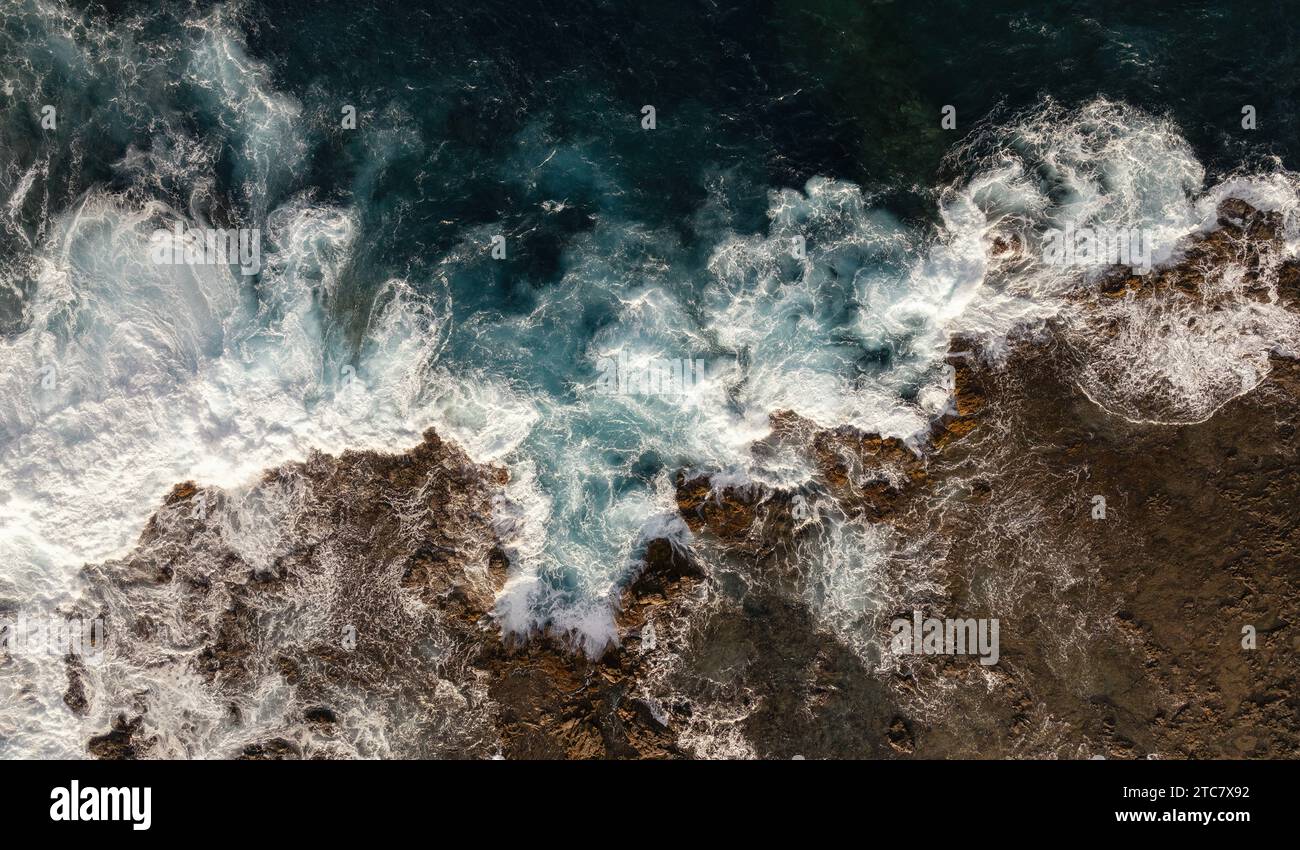 Aus der Vogelperspektive sehen turbulente Meereswellen, die auf die felsige Küste treffen und Schaum auf der Insel fuerteventura erzeugen Stockfoto