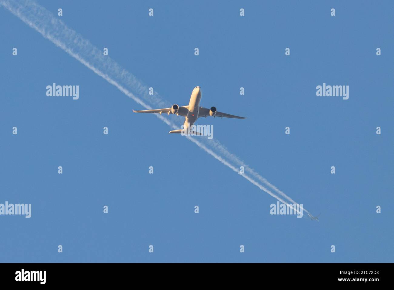 Singapore Airlines A350-941, reg 9V-SJB in geringer Höhe, nähert sich dem Flughafen Manchester zur goldenen Stunde mit einem Contrail eines anderen Flugzeugs in der Ferne Stockfoto