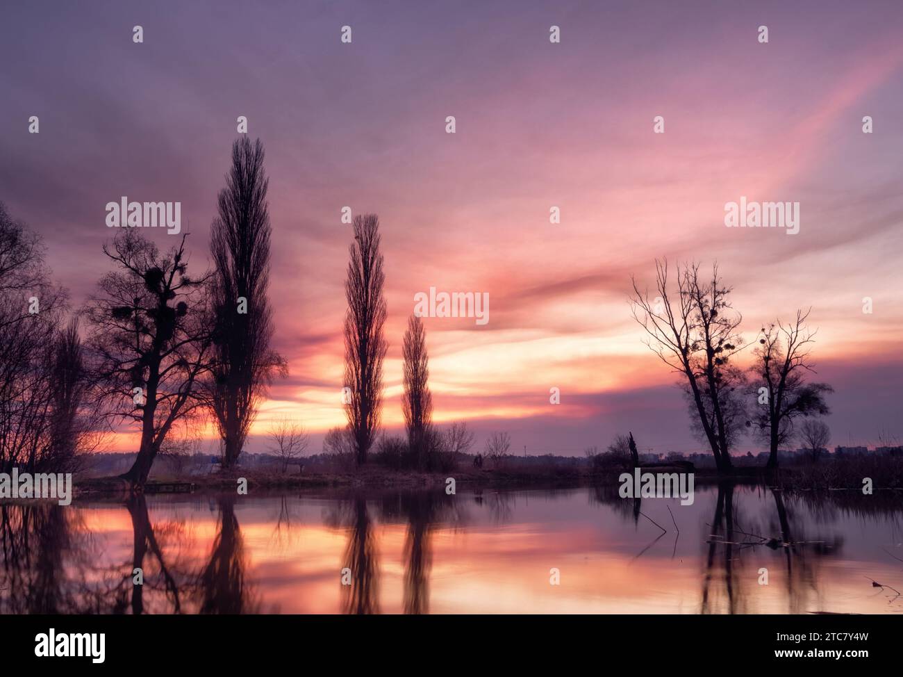 Dramatische Landschaft mit schönem glühenden Himmel mit Wolken über einem See bei Sonnenuntergang. Schönheit der Farben der Natur während der goldenen Stunde. Stockfoto