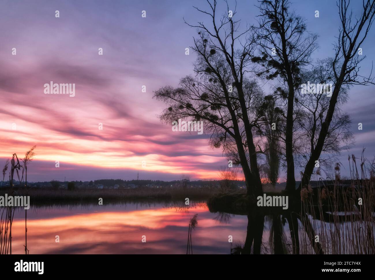 Dramatische Landschaft mit schönem glühenden Himmel mit Wolken über einem See bei Sonnenuntergang. Schönheit der Farben der Natur während der goldenen Stunde. Stockfoto
