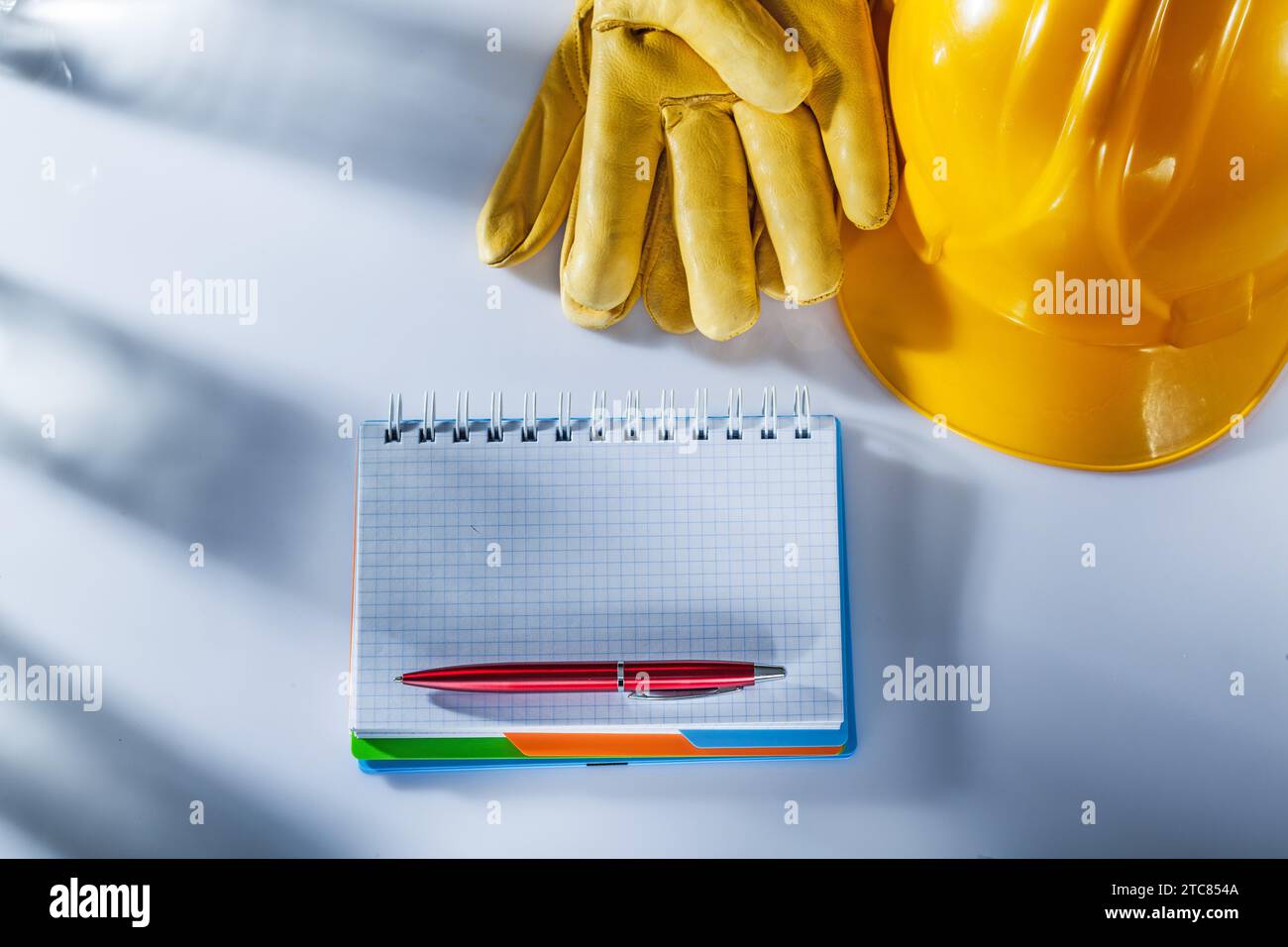 Sicherheitshandschuhe Schutzhelm Notizblock Stift auf weißem Hintergrund Stockfoto