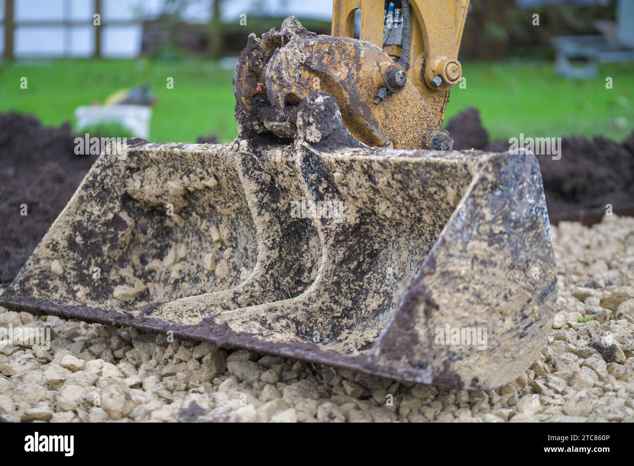 Minibagger-Planiereimer, der aus frisch gelegtem Kalkstein ruht Stockfoto