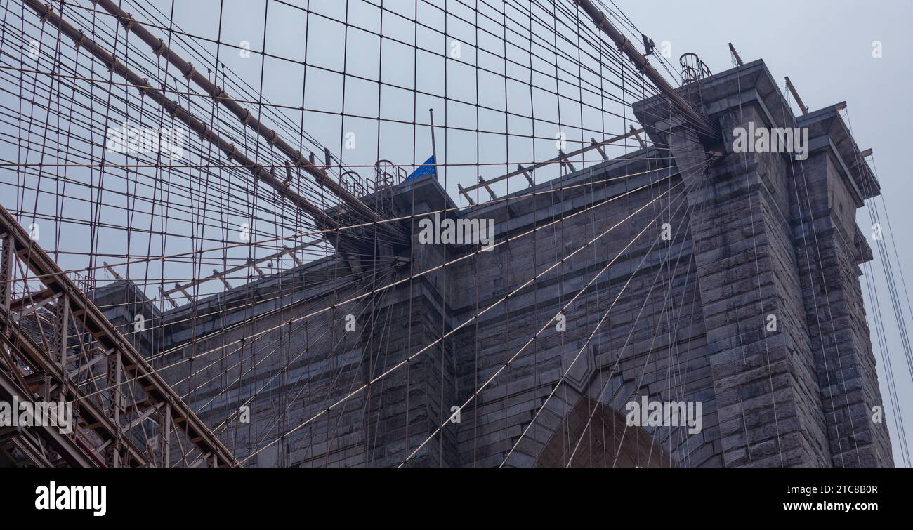Die Brooklyn Bridge, ein historisches Wahrzeichen von New York, ist ein Kabelnetz, das an massiven gotischen Steintürmen befestigt ist. Stockfoto