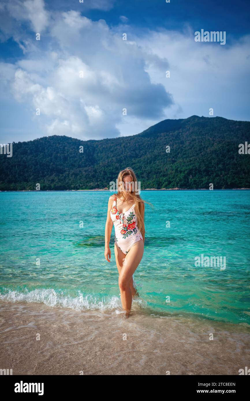 Die attraktive Frau in Badeanzug genießt die malerische Landschaft eines tropischen Strandes Stockfoto