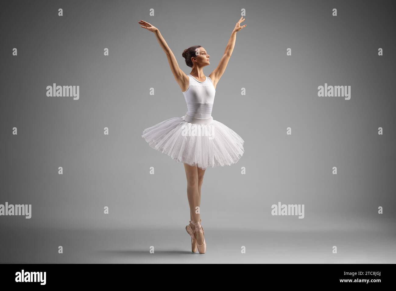 Aufnahme einer Ballerina in voller Länge, die isoliert auf grauem Hintergrund tanzt Stockfoto