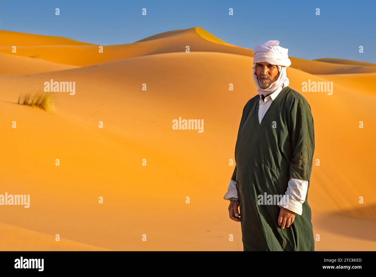 Marokkanischer Berbermann mit Kaftan und Turban in den Sanddünen von Erg Chebbi in der Sahara bei Merzouga, Drâa-Tafilalet, Errachidia, Marokko Stockfoto