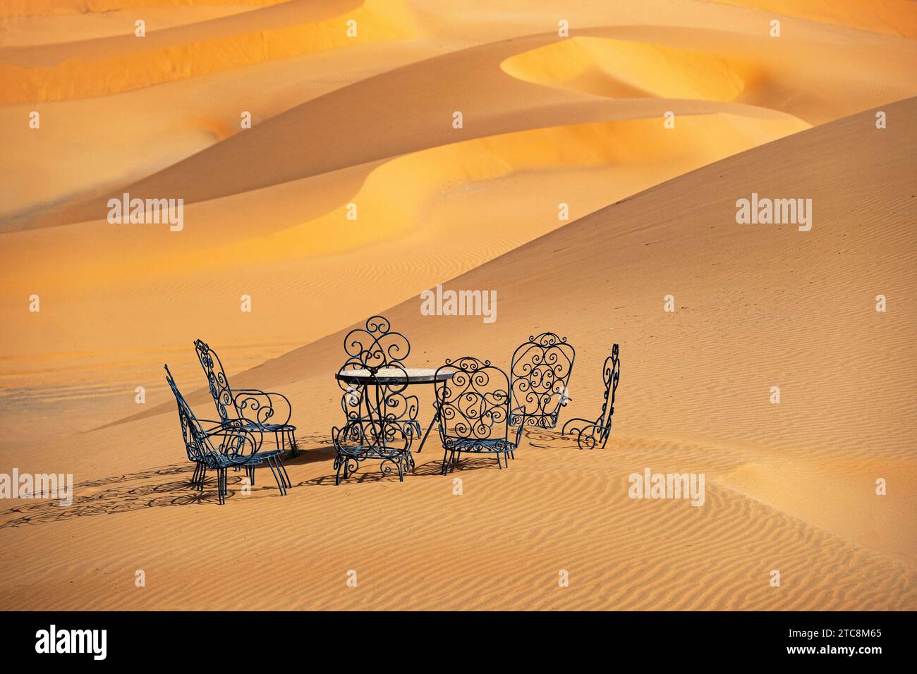 Gusseiserner Gartentisch und Gartenstühle in den Sanddünen von Erg Chebbi in der Sahara bei Merzouga, Drâa-Tafilalet, Errachidia, Marokko Stockfoto