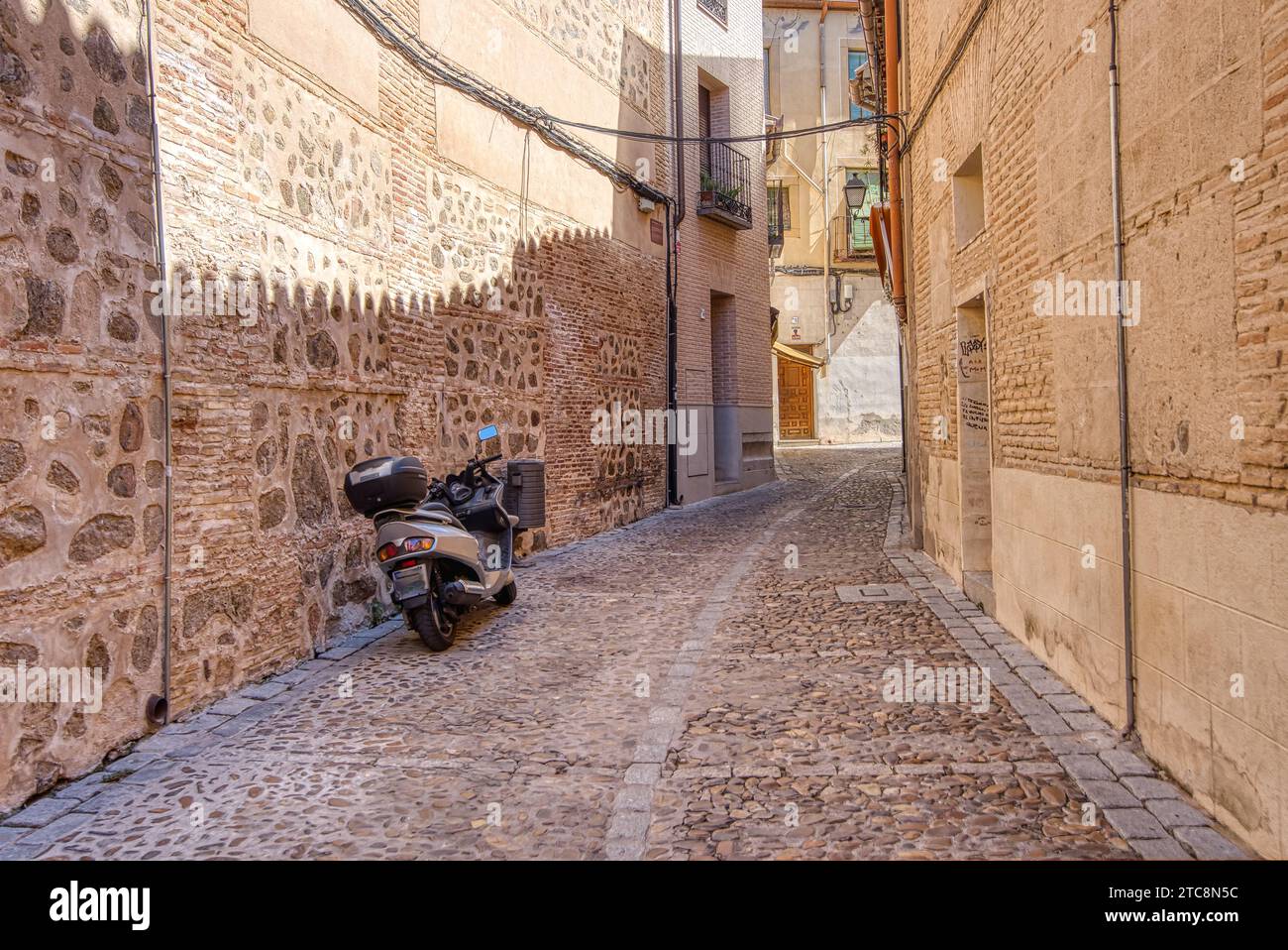 Motorrad parkt in einer alten engen Straße des historischen Toledo, Spanien Stockfoto