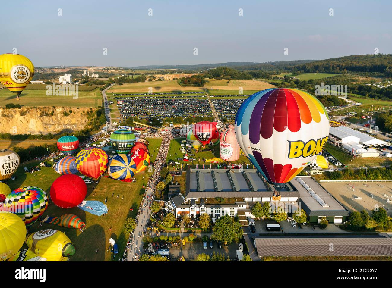 Bunte Heißluftballons beim Massenstart, Menschenmenge auf dem Messegelände, Heißluftballonfestival, 26. Warsteiner International Montgolfiade, aus der Luft Stockfoto