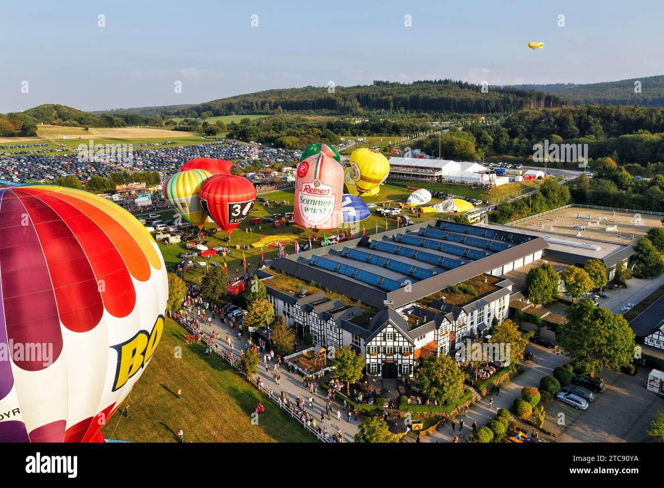 Bunte Heißluftballons beim Massenstart, Menschenmenge auf dem Messegelände, Heißluftballonfestival, 26. Warsteiner International Montgolfiade, aus der Luft Stockfoto