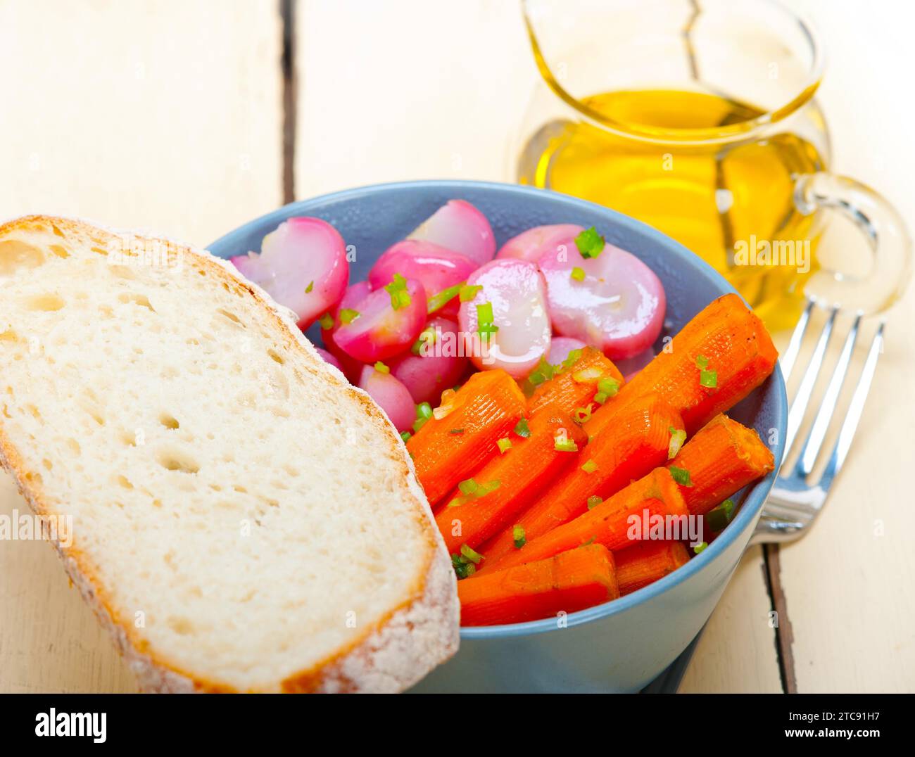 Schüssel mit gedämpftem Wurzelgemüse auf einem rustikalen weißen Holztisch Stockfoto