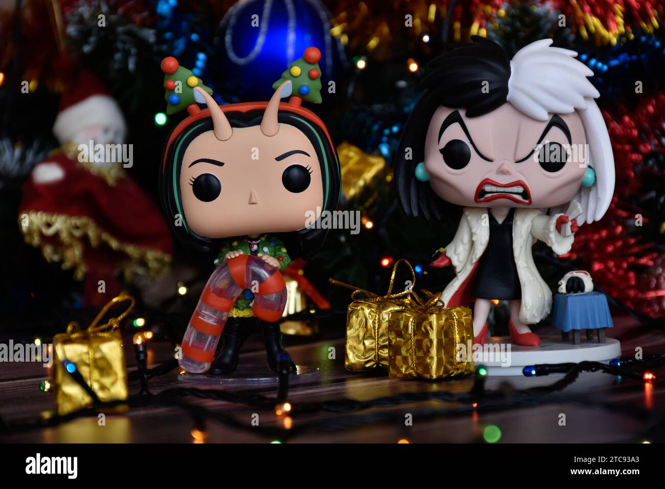 Funko Pop Actionfiguren von Mantis von Guardians of the Galaxy und Disney-Bösewicht Cruella de Vil. Weihnachtsbaum, Geschenkboxen, bunte Lichter. Stockfoto