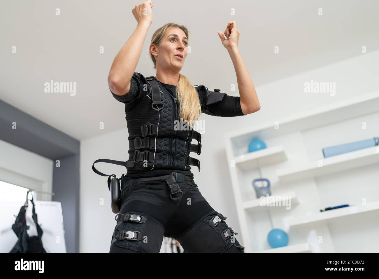 Frau im EMS-Trainingsraum, die Aerobic-Bewegungen in einem Fitnessstudio durchführt Stockfoto