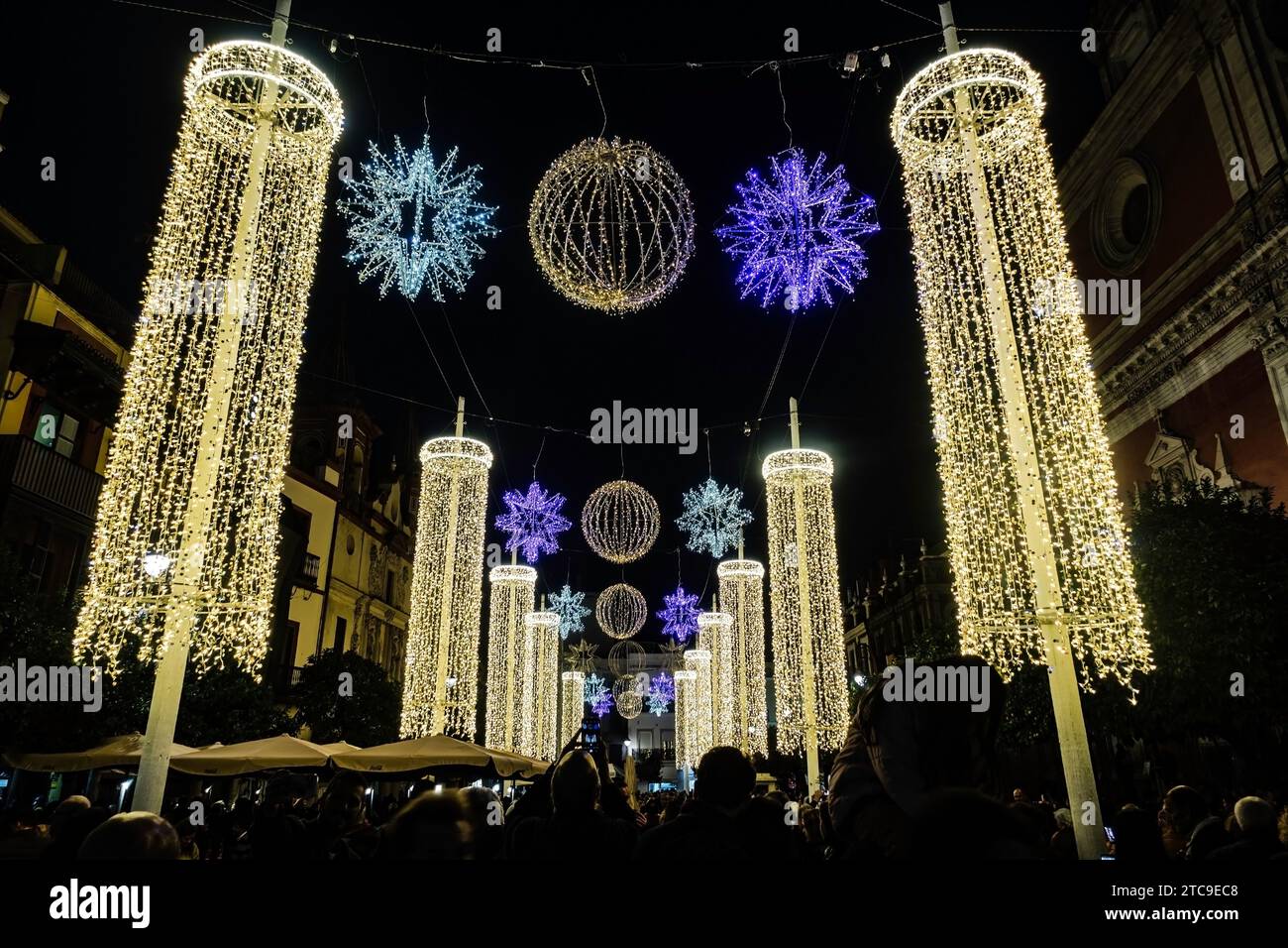 Elegante Holiday Light Säulen und Schneeflocken, majestätische Säulen aus Weihnachtslichtern und glitzernde Schneeflocken funkeln in der Nacht. In Sevilla, Spanien. Stockfoto
