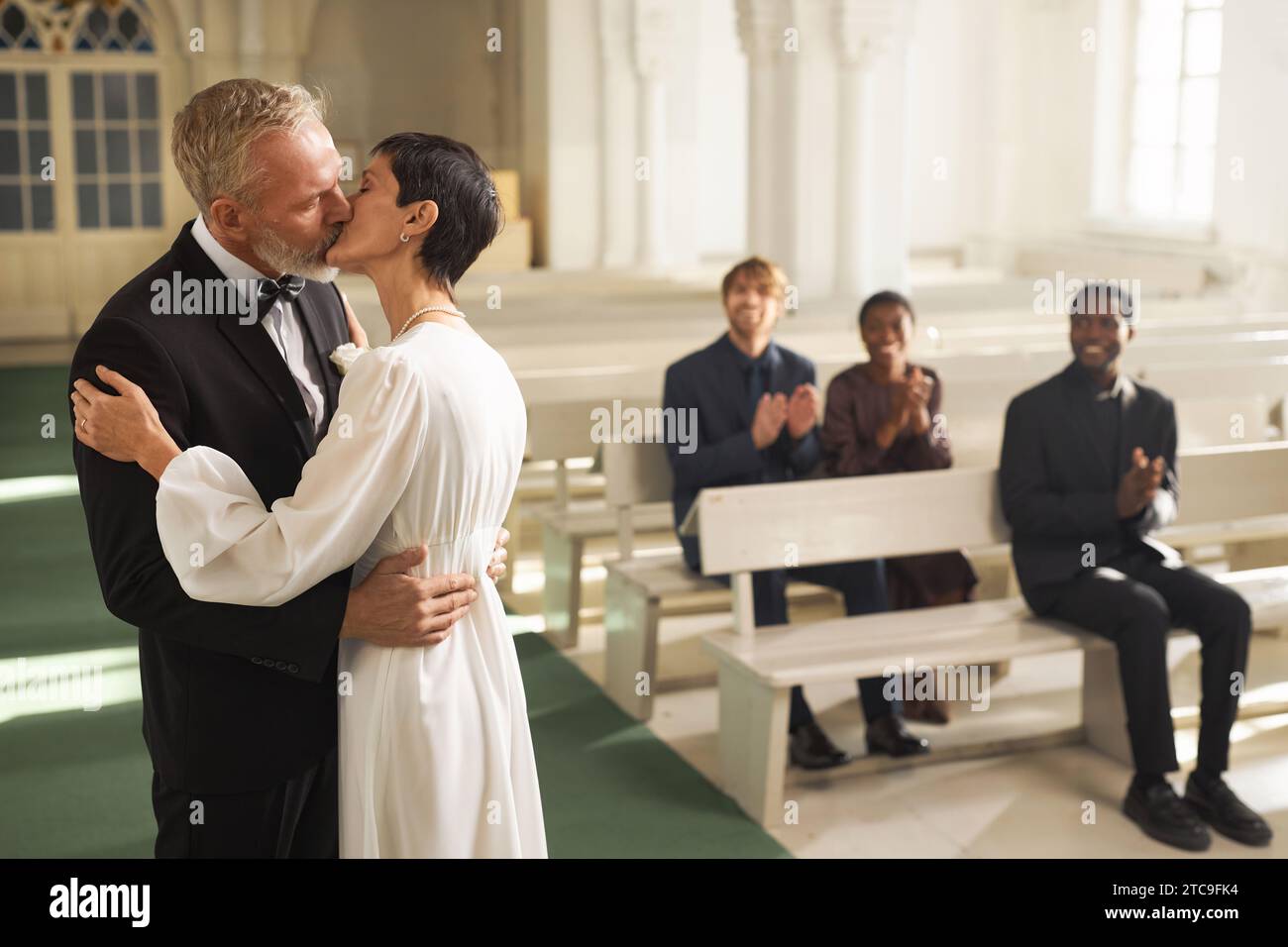 Seitenansicht Porträt des liebenden Seniorenpaares beim ersten Kuss in der Kirche am Hochzeitstag, Kopierraum Stockfoto