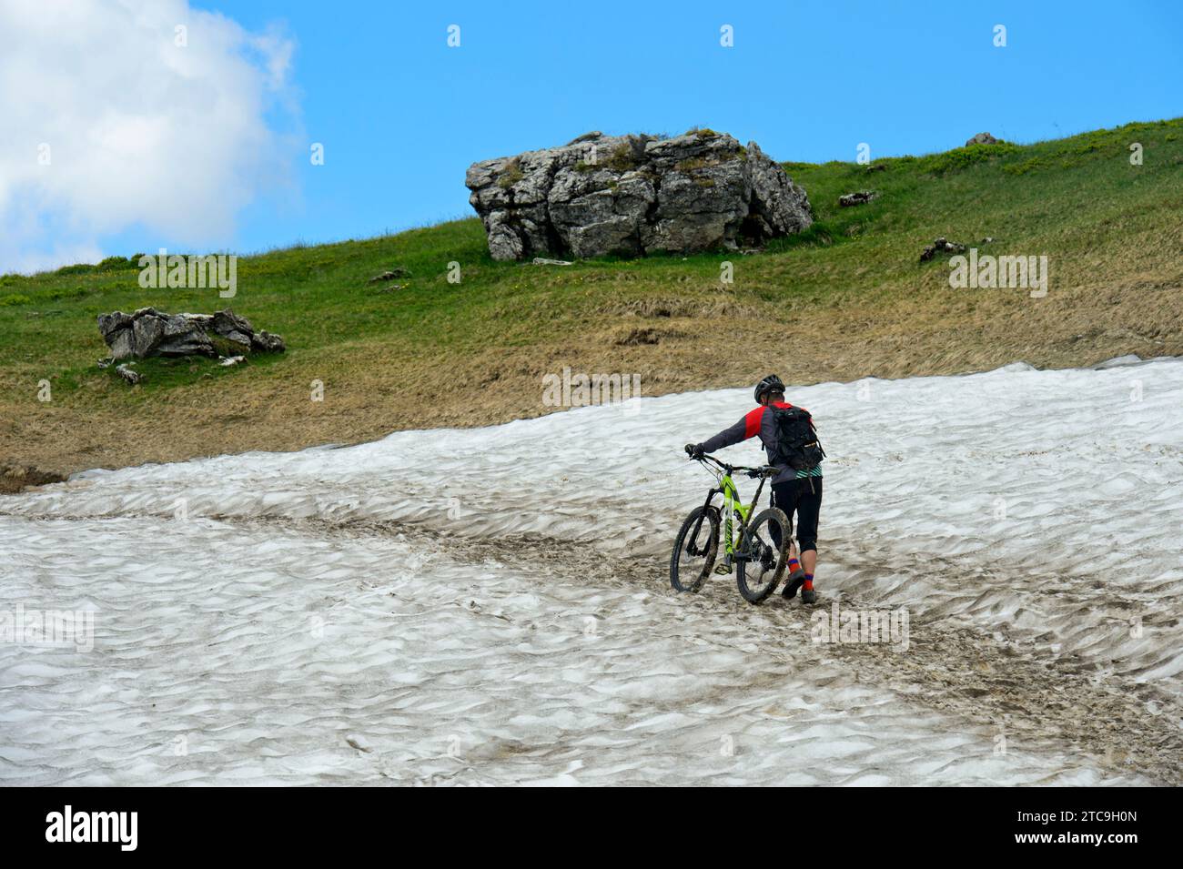 Mountainbiker schiebt sein Mountainbike über Ein Schneefeld, Montriond, Chablais, Frankreich Stockfoto