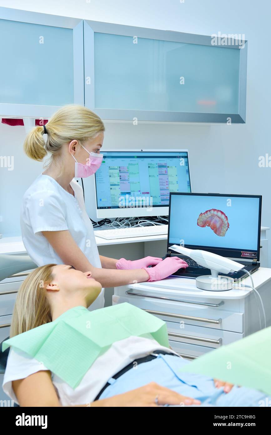 Kieferorthopäden und Patienten sehen sich das Ergebnis eines 3D-Scans auf einem Laptop-Bildschirm an. Modernes Zahnheilkunde- und Gesundheitskonzept. Stockfoto