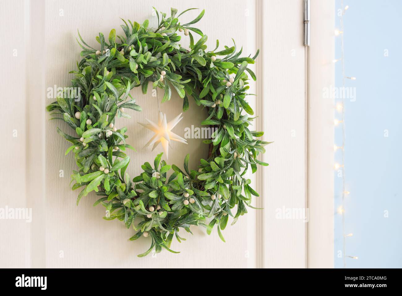 Weiße Tür mit weihnachtlichem Mistelkranz, Nahaufnahme Stockfoto