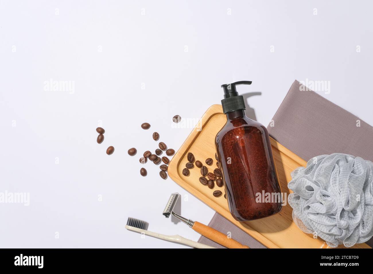 Eine braune Shampooflasche ist auf einem Holztablett mit Kaffeebohnen auf weißem Hintergrund zu sehen. Leerraum für Textdesign. Ansicht von oben, Kopierbereich Stockfoto