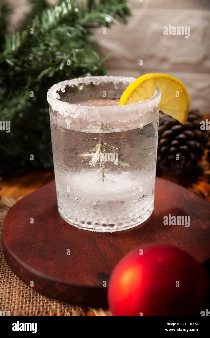Schneekugel-Cocktail. Weihnachtsgetränk, kreatives Festgetränk im Glas, dekoriert mit Rosmarinzweig wie eine weihnachtskiefer, Zitrusscheibe Stockfoto
