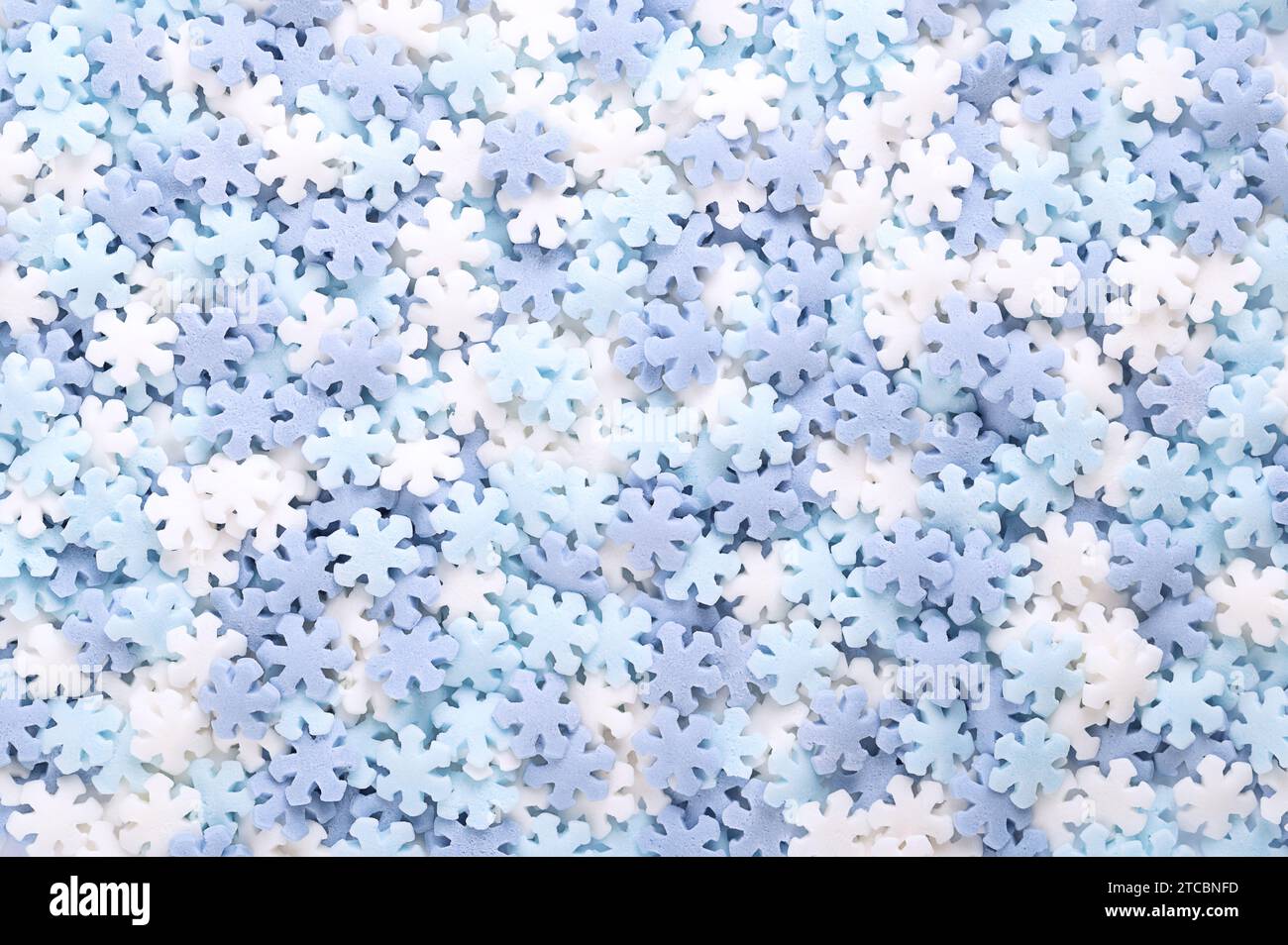 Schneeflockenförmige Zuckerstreusel. Hintergrund von blauen und weißen Konfetti-Bonbons, Süßwaren aus Zucker und Reis, bestehend aus flachen Süßigkeiten-Streuseln. Stockfoto