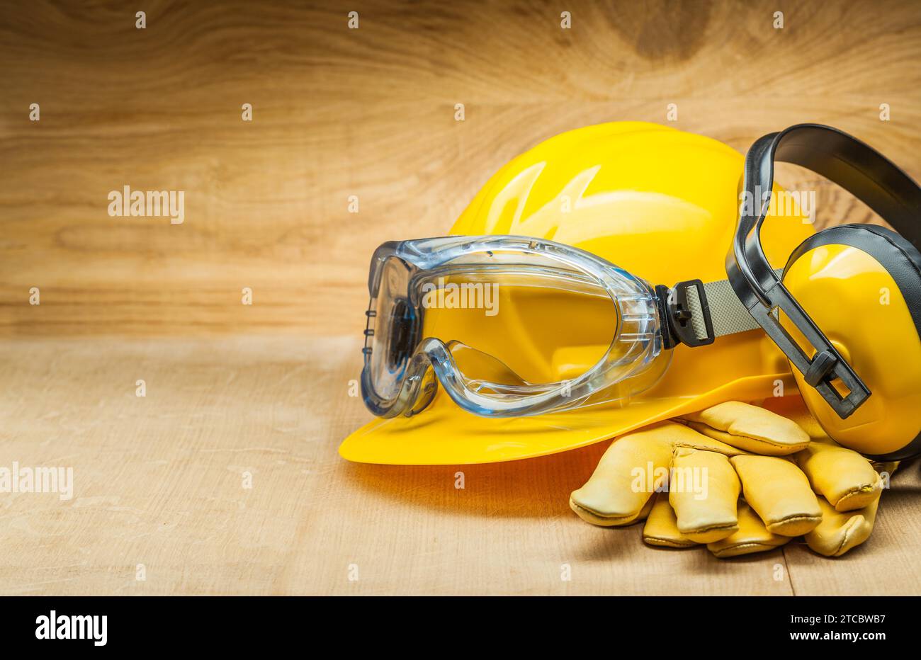 Sicherheitskonzept. Sicherheitswerkzeuge für den Bau. Gelber Konstruktionshelm, Lederhandschuhe und Kopfhörer Stockfoto