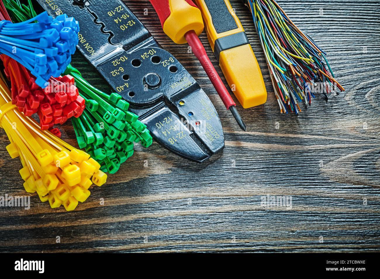 Elektrischer Tester Kabelbinder Bolzenschneider Isolationsschraubendreher auf Holzplatte Stockfoto