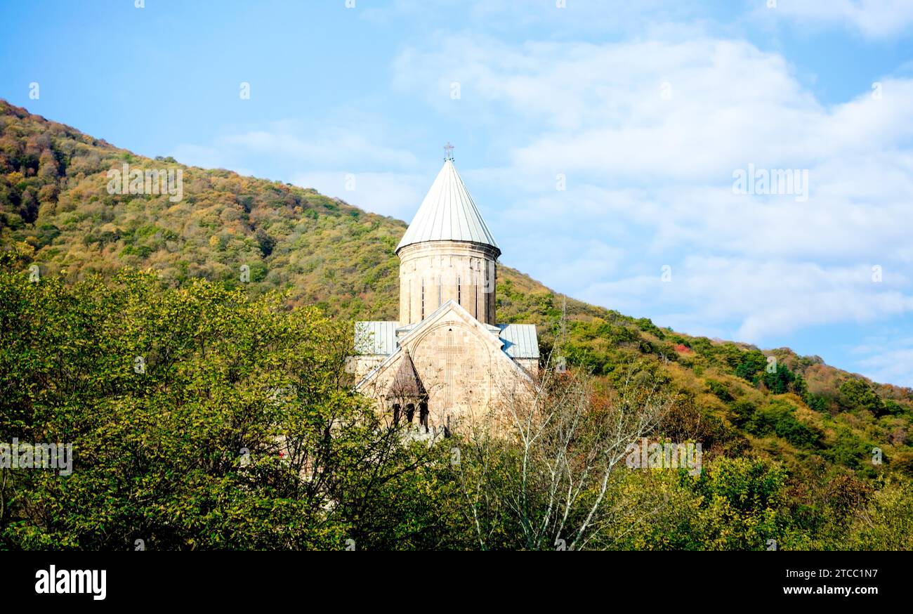 Alte antike christliche Kirche mit Kuppel und Kreuz auf einem Berg in einem Wald in Tiflis Georgien vor blauem Himmel und Wolken Stockfoto