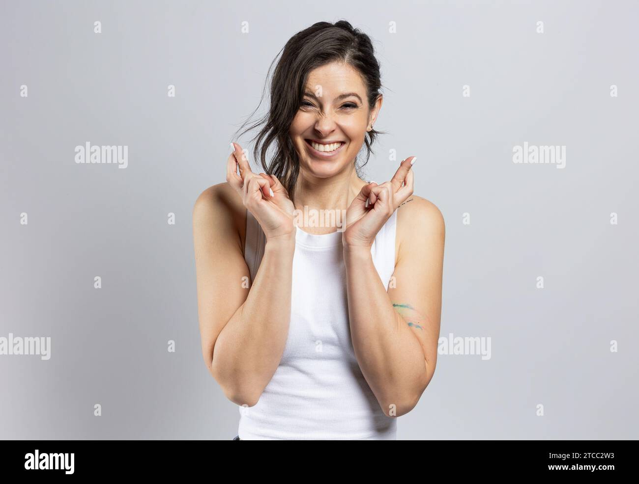 Porträt einer sehr attraktiven Frau, die Erfolg mit gekreuzten Fingern wünscht, isoliert auf grauem Hintergrund Stockfoto