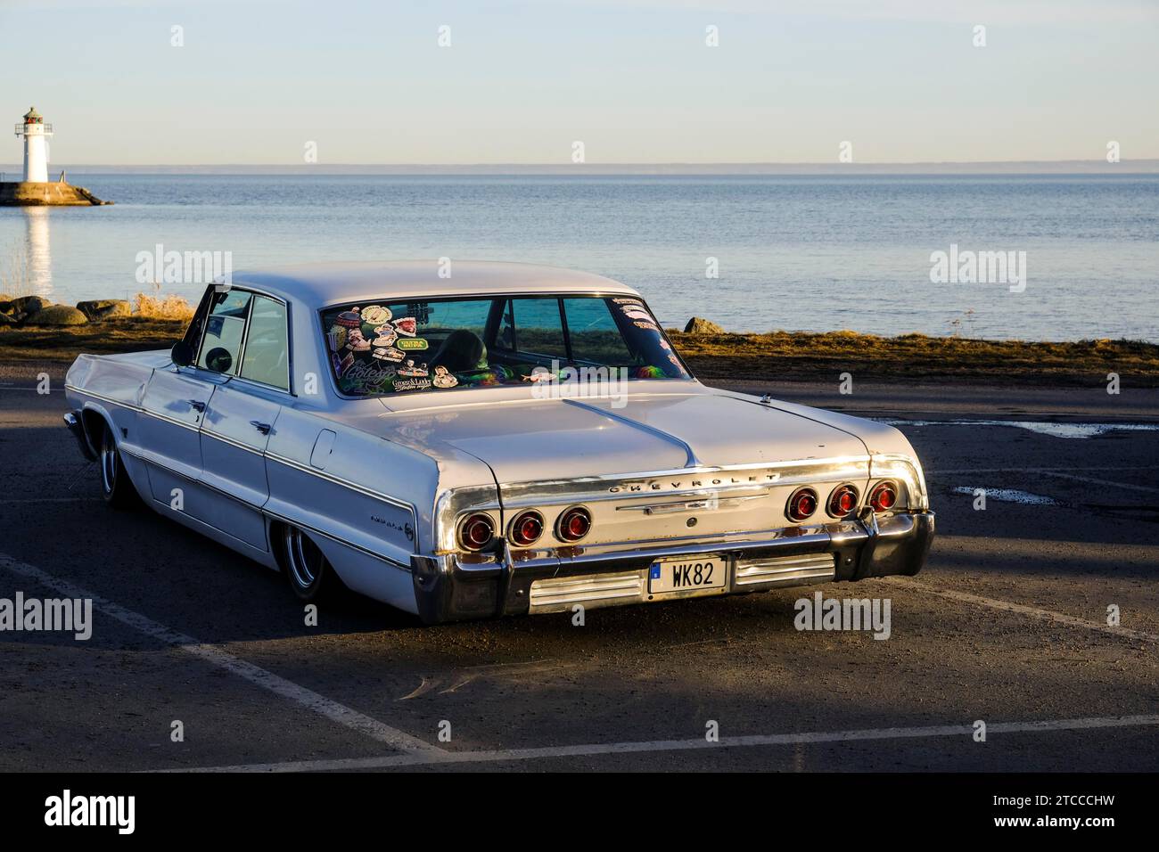 Amerikanischer Oldtimer, Chevrolet Impala von 1964, hinter dem See Vaettern und dem Leuchtturm von Hjo, Hjo, Vaestra Goetaland, Schweden Stockfoto