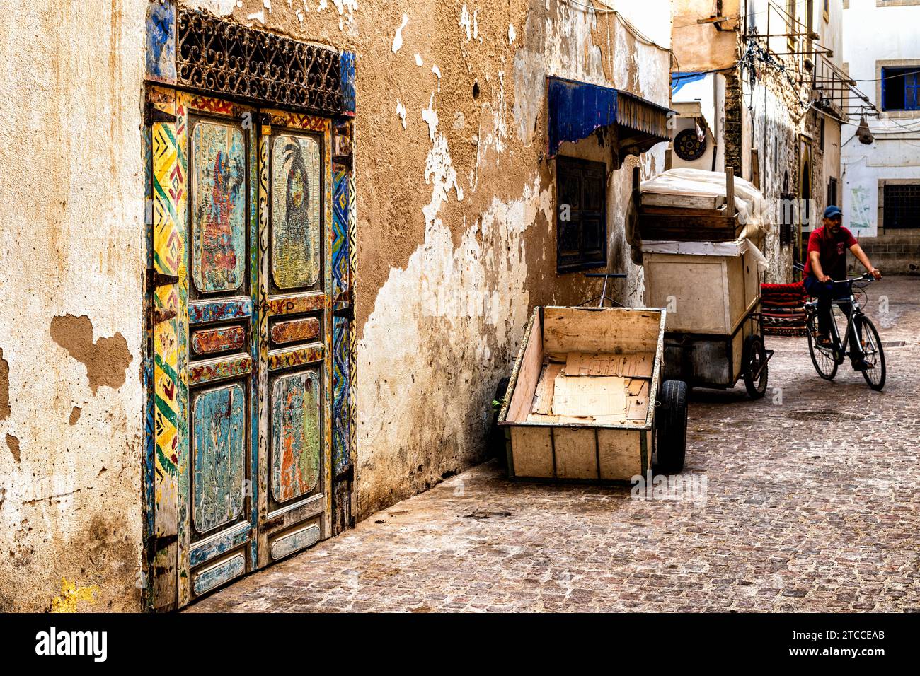 Essaouira, Marokko: Farbenfrohe Holztür mit Blick auf eine enge Gasse innerhalb der Stadt Medina. Marokkanisches Stadtbild. Stockfoto