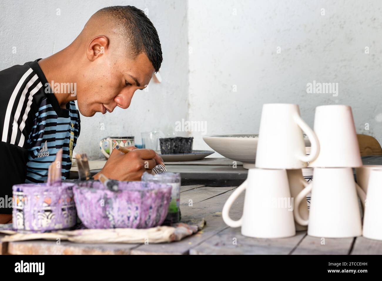 Fes, Marokko: Marokkanische Handwerker malen Keramikbecher und -Tassen in einer Werkstatt in Fes Medina. Stockfoto