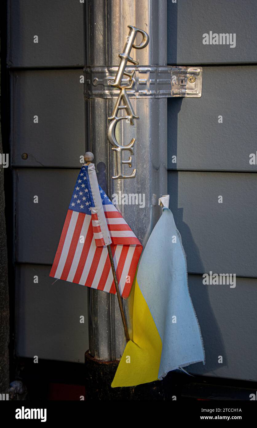 Die USA und die Ukraine fahnen Seite an Seite vor einem Metall-Friedensschild Stockfoto