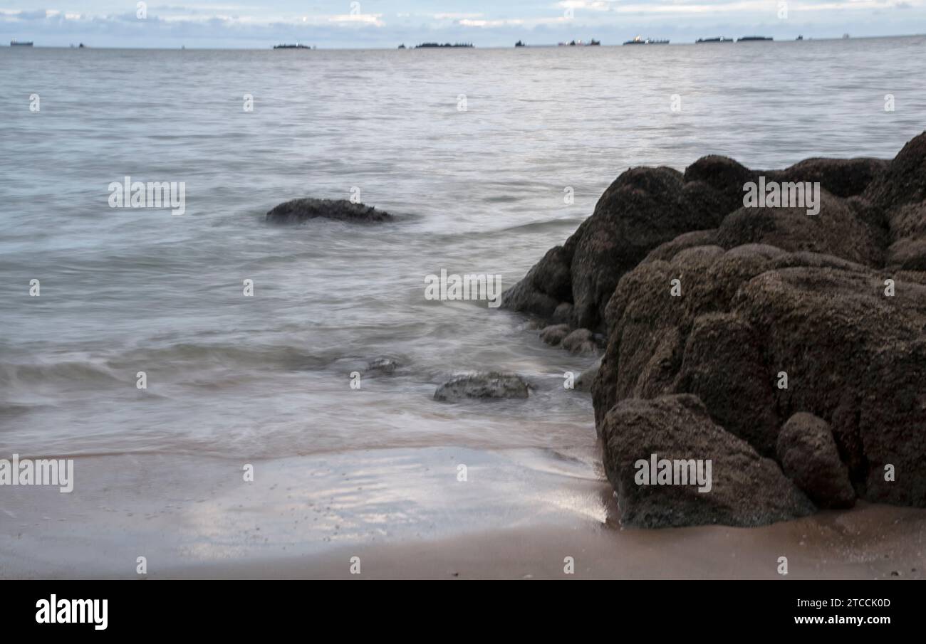 Langsame Aufnahmen der Meereswellen entlang des felsigen Strandes. Stockfoto