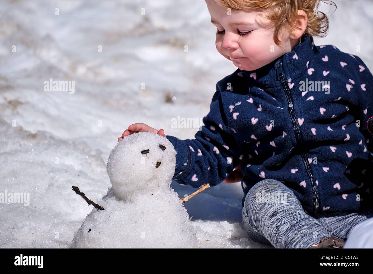 Niña pequeña jugando con un muñeco de nieve por primera vez en hinvierno en la Vall de Núria Stockfoto