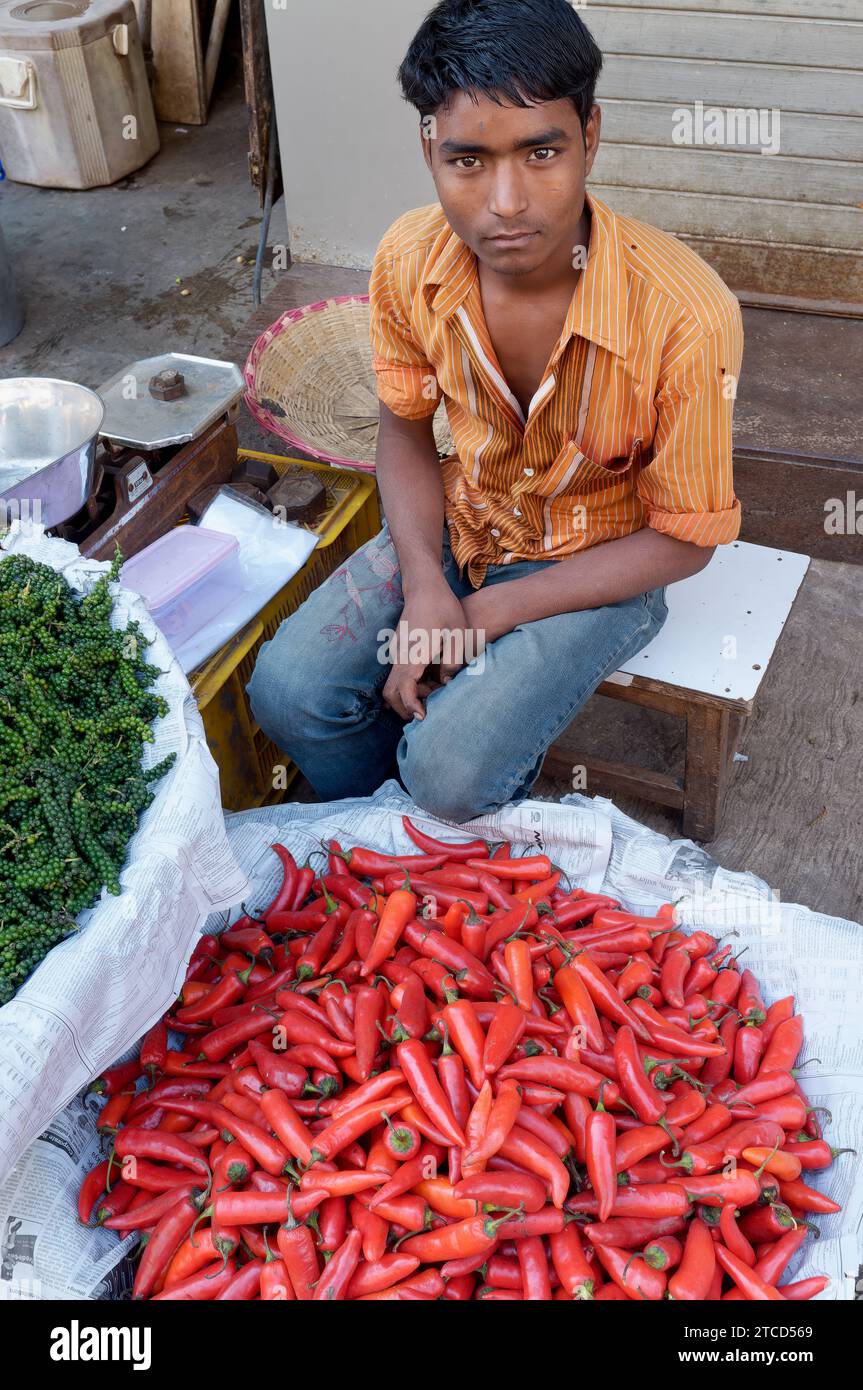 Ein junger Indianer, der auf einer Straße in Mumbai sitzt und rote Chili und junge schwarze Pfeffer verkauft (l) Stockfoto