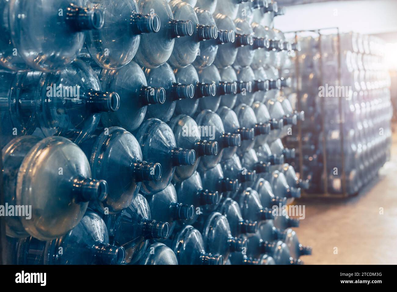 Trinkwasser-saubere Gallonen-Flaschen stapeln sich im Lagerlager in der Trinkwasserfabrik und warten in der Schlange auf die Wasserabfüllung im Werk. Stockfoto