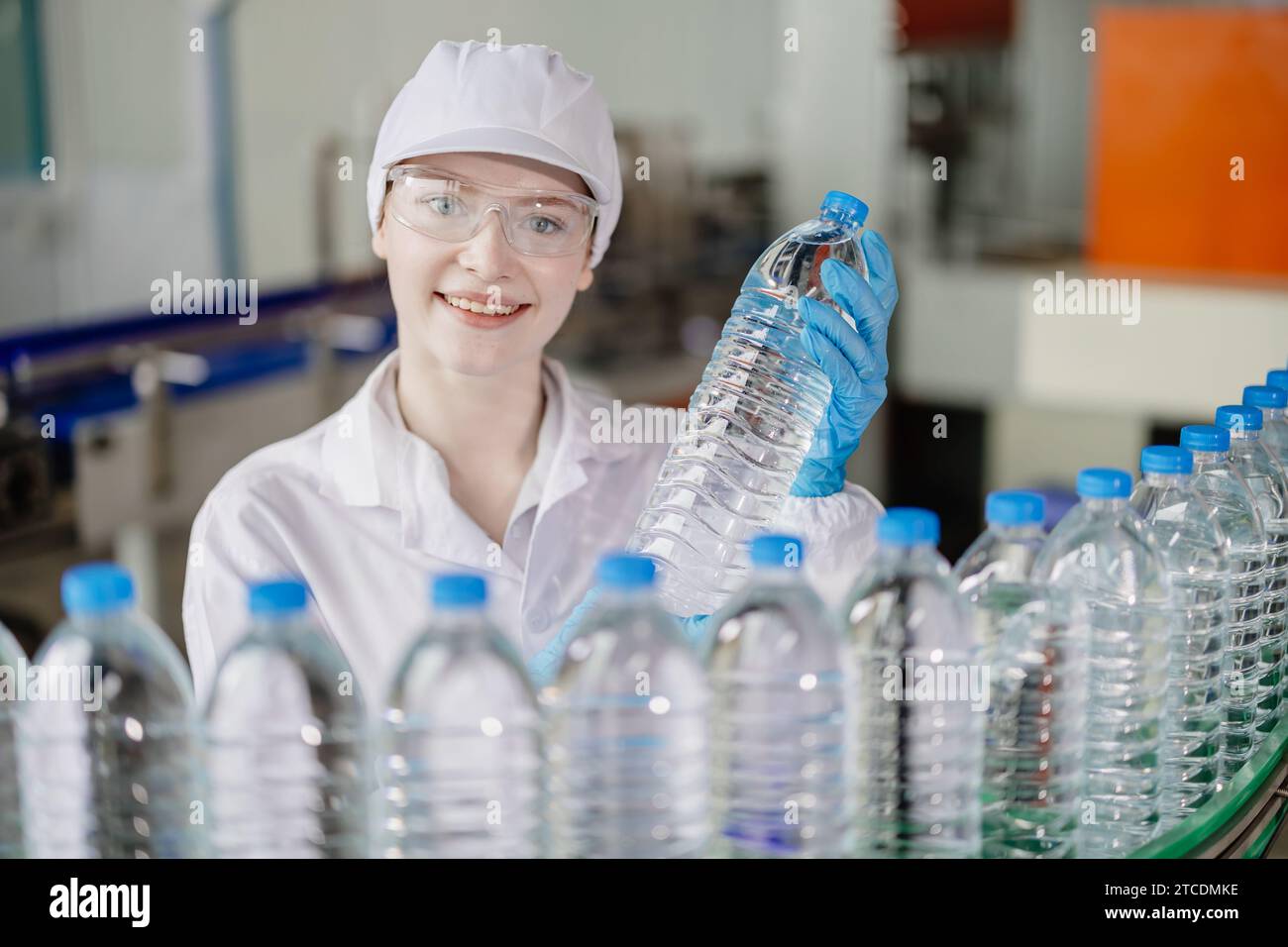 Porträt lächelnde junge kaukasische Frauen Arbeiter mit Trinkflaschen arbeiten an der Fabrikproduktionslinie der Trinkwasseranlage Qualitätskontrolle. Stockfoto